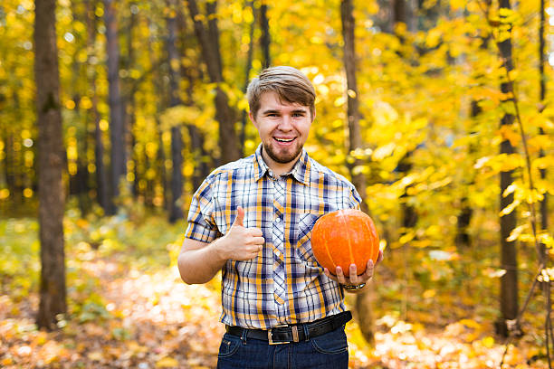 istock Smiling man carrying pumpkin outdoors 493977318