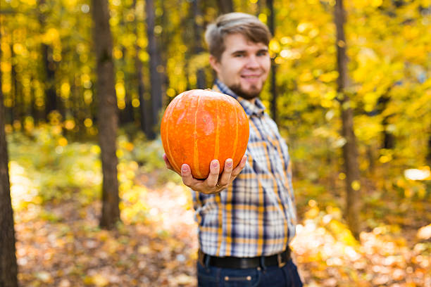 istock Smiling man carrying pumpkin outdoors 493977340