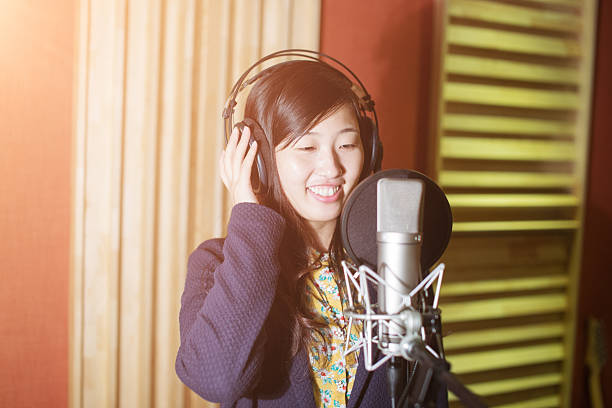 Young male singer recording song in professional music studio