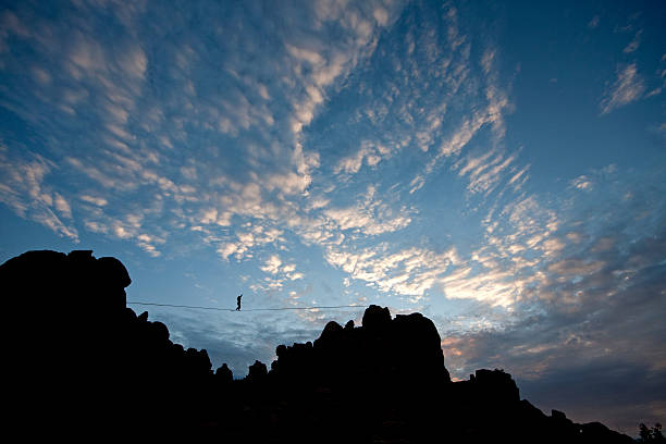 Highline walker in patchy sky Highline walker silhouetted in patchy sky, Joshua Tree National Park highlining stock pictures, royalty-free photos & images