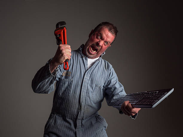 Angry Repairman Takes To Computer Keyboard with a Pipe Wrench stock photo