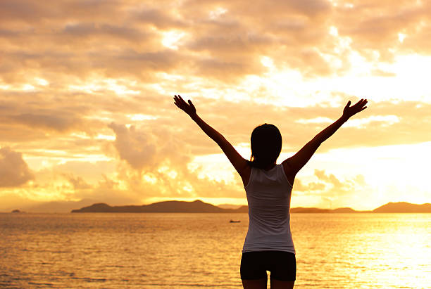 istock cheering woman open arms to sunrise seaside 493983365