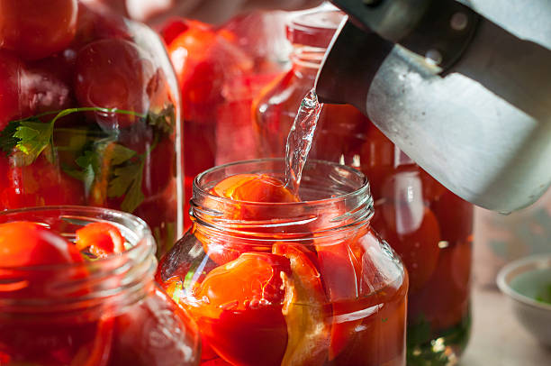 Canning process of tomato in mason jar. On background is