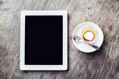 Blank digital tablet and cup of coffee on a wooden table