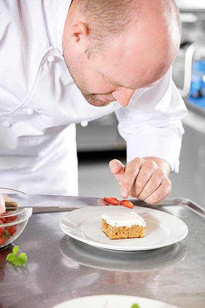 istock Chef decorates dessert cake with strawberry in kitchen 493997932