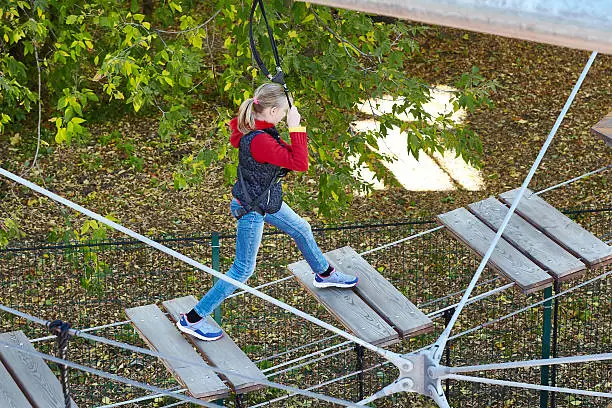 Girl athlete runs an obstacle course in climbing amusement park