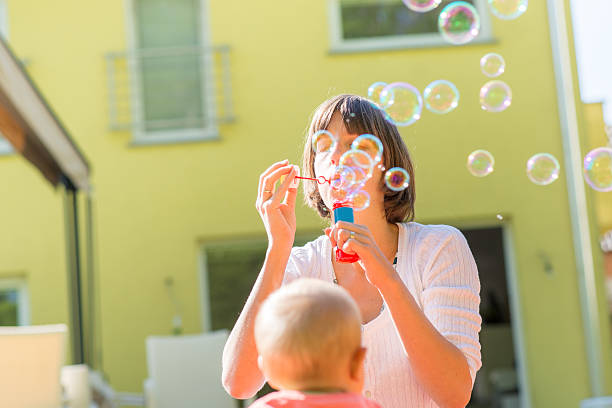 istock Cheerful young mother standing outdoors blowing bubbles for her 494001904