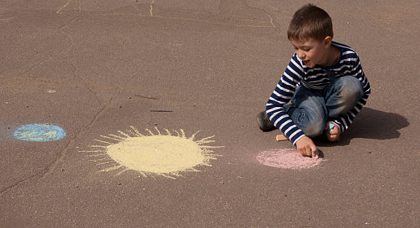 istock Boy drawing space and planets on the pavement 494003234