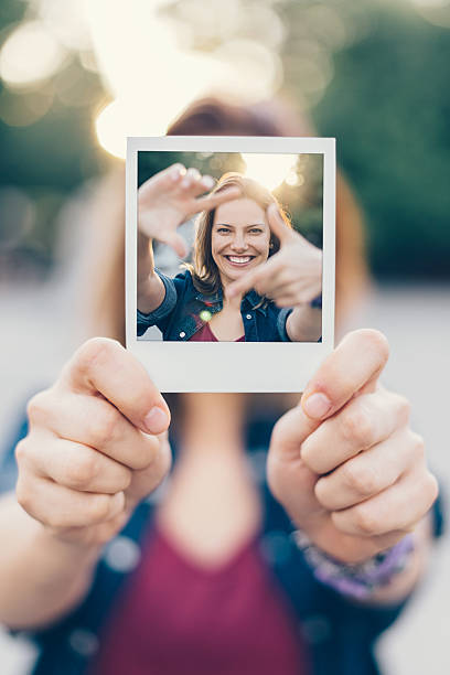 dziewczyna trzyma zestaw polaroid selfie - focus finger frame frame human hand zdjęcia i obrazy z banku zdjęć