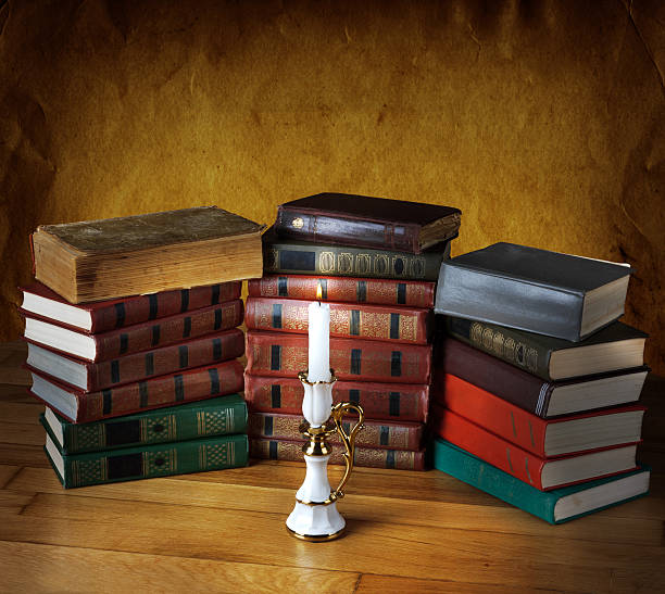 istock Old stack of books with candlestick and burning candle 494034349