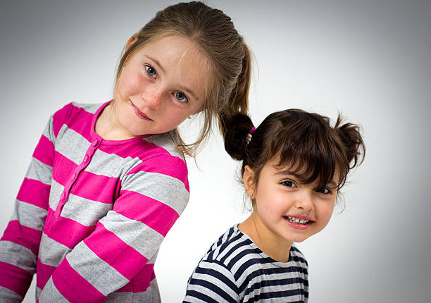 Portrait of two cute little sisters at home on beautiful summer day. Sibling love concept.