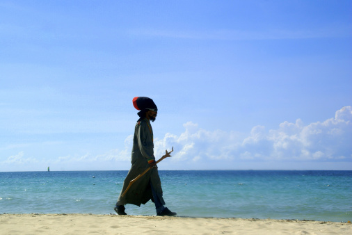 Man walking on the beach by the sea at Ko Phangan Island, Thailand.