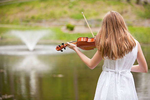 istock Young Girl Playing Viola By Pond 494056289