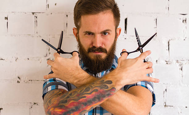 istock Young bearded barber with tattoo and pair of black scissors 494058486