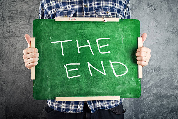 istock Man holding green chalkboard with THE END title 494059285