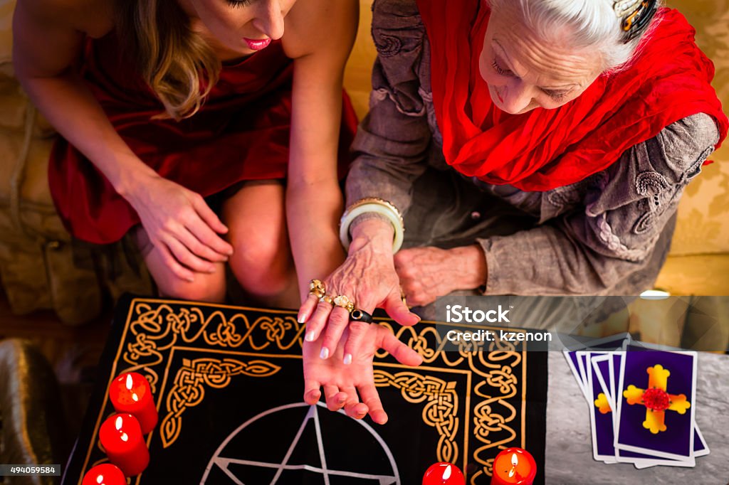 Soothsayer during a session doing palmistry Female Fortuneteller or esoteric Oracle, sees in the future by hand reading during a Seance to interpret them and to answer questions Fortune Telling Stock Photo
