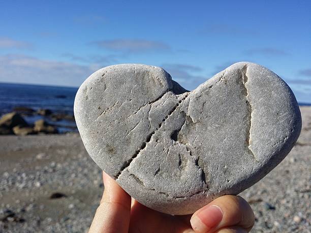 istock holding rock heart on the beach 494062802