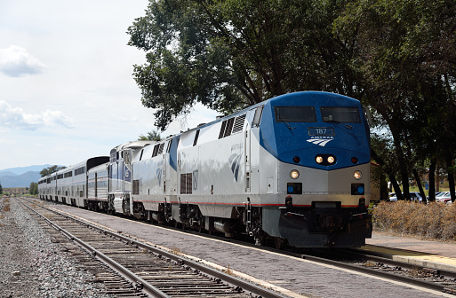 Lamy, United States - September 8, 2015: The eastbound Amtrak Southwest Chief passenger train at Lamy, New Mexico, USA. The train has travelled overnight from Los Angeles and is heading for Chicago. The train is powered by a pair of GE P42DC, numbers 187 and 198, and a single EMD F59PHI locomotive, number 455, all diesels. This train, and its westbound counterpart, are the only two trains to traverse this route per day as it has no freight service. Unidentified crew.