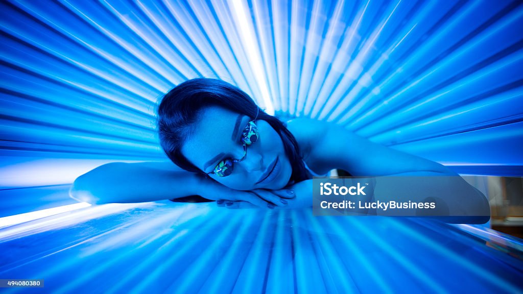 Beauty in solarium. Attractive young woman tanning in solarium and smiling. Tanning Bed Stock Photo