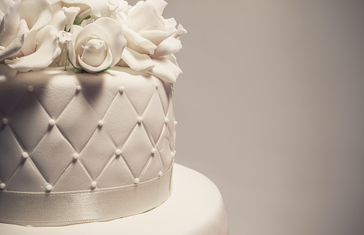 Details of a wedding cake, decoration with white fondant on gray background.