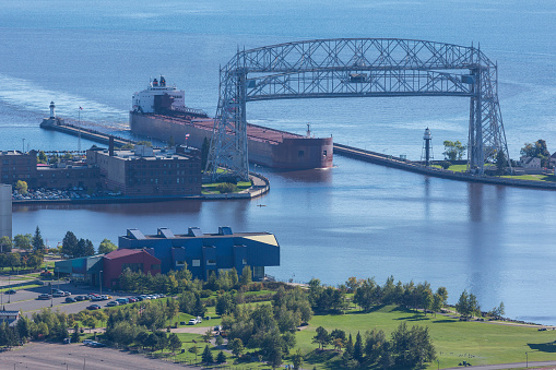 A ship entering a harbor on Lake Superior through a canal.