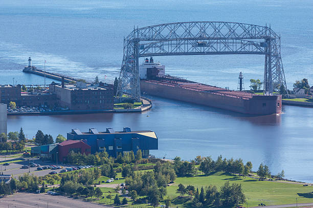 Ship Entering Harbor A ship entering a harbor through a canal on Lake Superior. cantilever bridge stock pictures, royalty-free photos & images