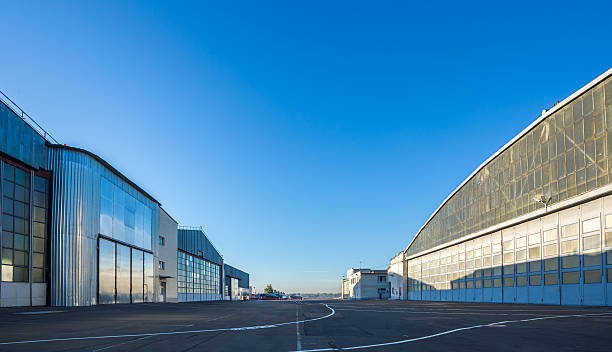 The area between aircraft hangars The area between aircraft hangars. Buildings are large and gray on the road with aviation markings. The weather is sunny with blue clear sky. military base stock pictures, royalty-free photos & images