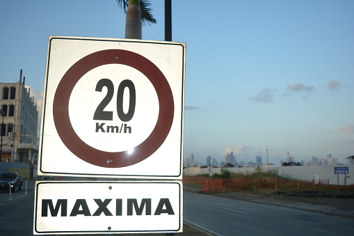 Temporary 30km speed limit sign on a busy suburb shopping street. Out-of-focus Detour Ahead signs along the road. Roadworks on Auckland roads.