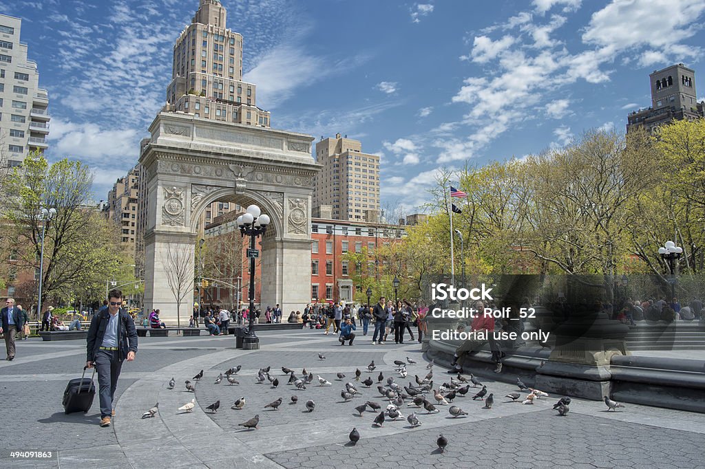 Springtime in New York City New York, USA – May 1, 2014: A traveller pulls a roller bag on sunny spring day in Washington Square Park - an iconic park and a center for cultural activity in Greenwich Village. New York University Stock Photo