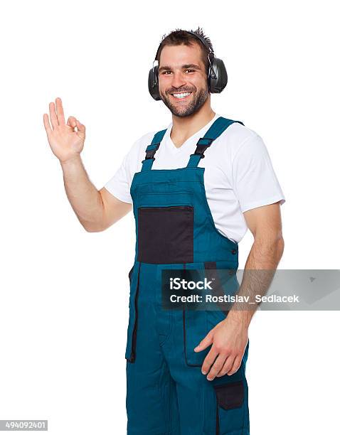 Smiling Worker In Green Uniform With Protective Earphones Stock Photo - Download Image Now