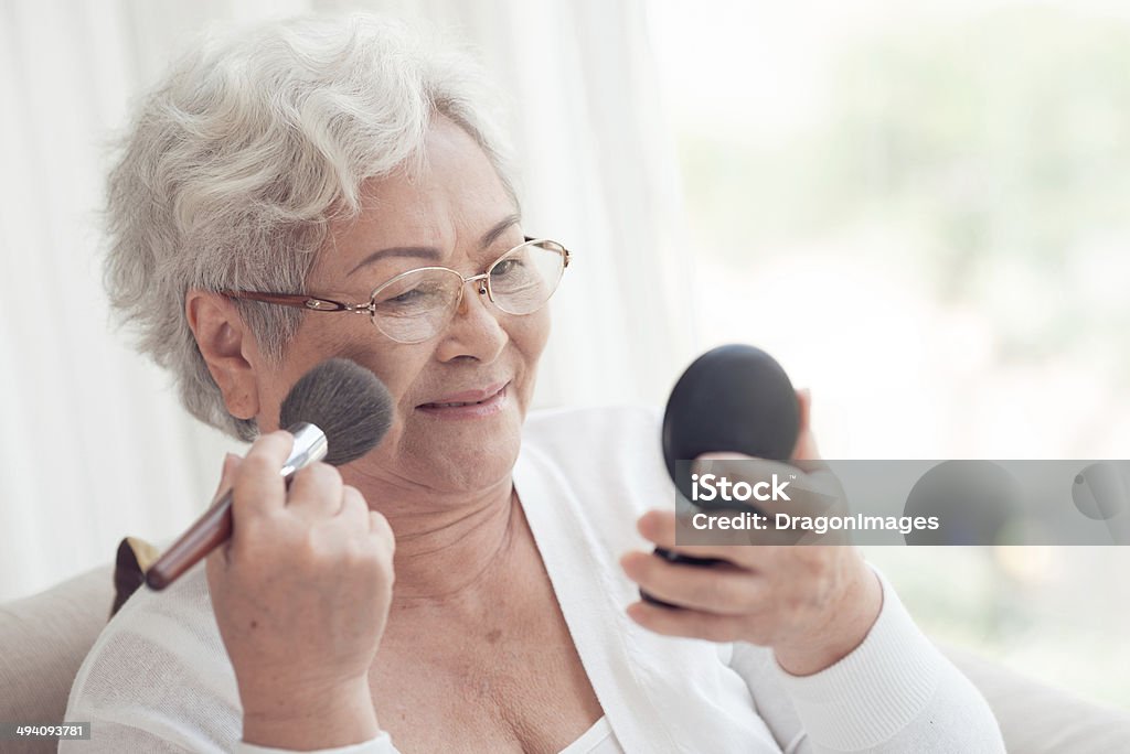 Blush Aged Asian woman applying blush with a make-up brush Adult Stock Photo