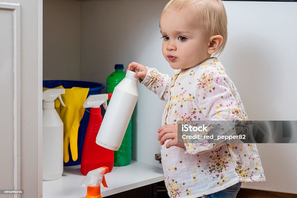 Little girl playing with household cleaners Toddler playing with household cleaners at home Child Stock Photo