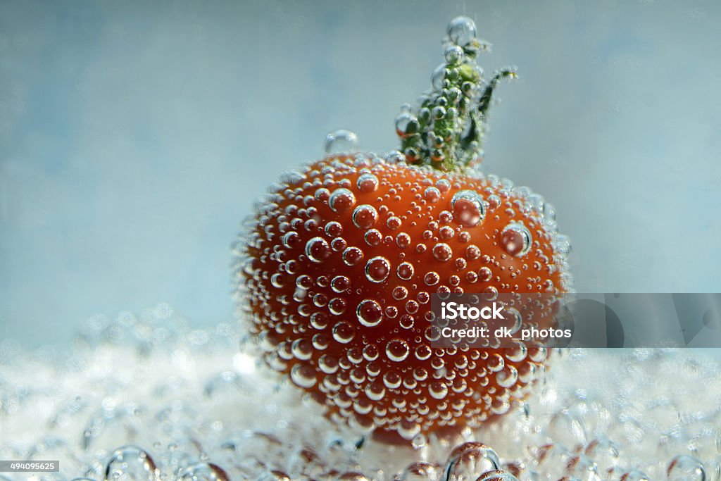 cherry tomato with bubbles underwater Photo of a cherry tomato with bubbles underwater on a blue background. Creative food photography. Art Stock Photo