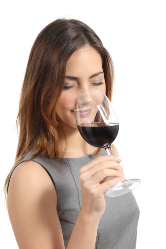 Beautiful sommelier woman tasting wine isolated on a white background