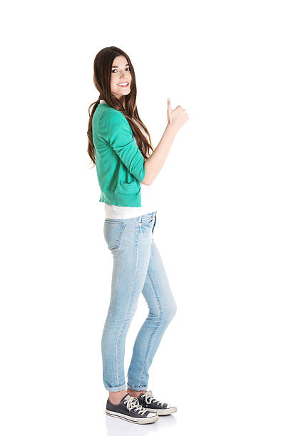 Smiling attractive woman in long white skirt and black top pointing or touching something and looking away, Full length studio shot isolated on white.