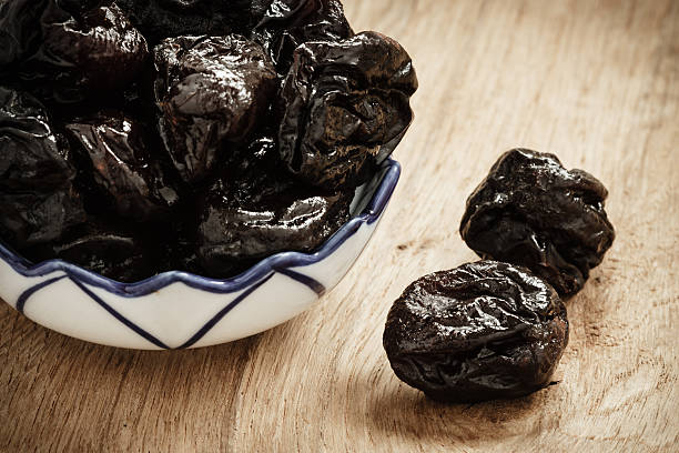 istock dried plums prunes in bowl on wooden table 494119826