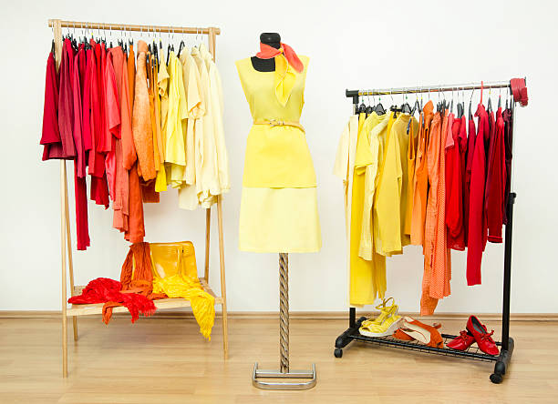 istock Wardrobe with yellow, orange and red clothes arranged on hangers. 494120855