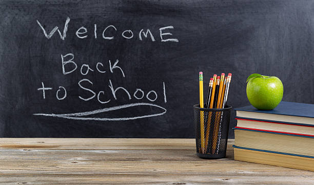 istock Old wooden desktop with simple school supplies and blackboard 494120984