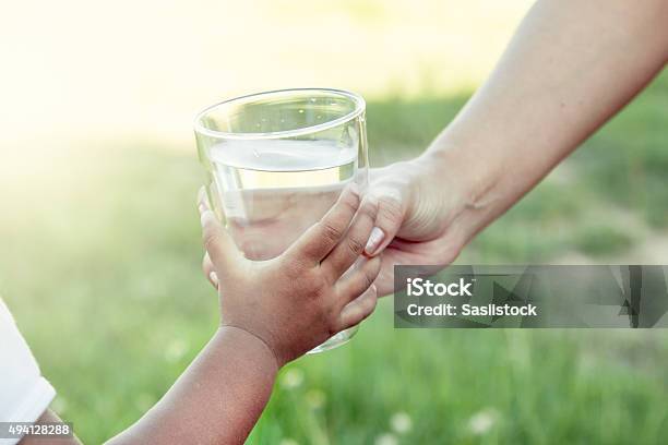 Woman Hand Giving Glass Of Fresh Water To Child Stock Photo - Download Image Now - Child, Drinking Water, Glass - Material