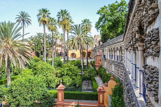 Alcazar gardens in Seville, Spain Seville, Spain - August 11, 2015: The gardens of the Alcazar palace in Seville, Spain. Photo taken during the day and features several tourists enjoying the atmopshere of the gardens. santa cruz seville stock pictures, royalty-free photos & images