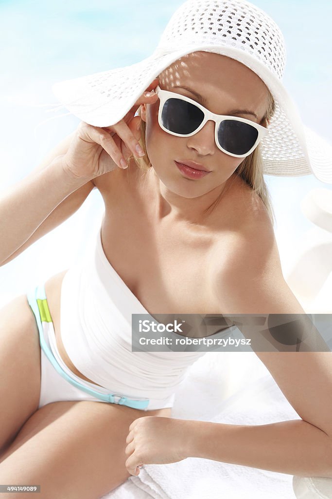 Sun holiday ­ relaxing on the beach Beautiful, attractive girl in costume and hat relaxing on a sunny beach. Adult Stock Photo
