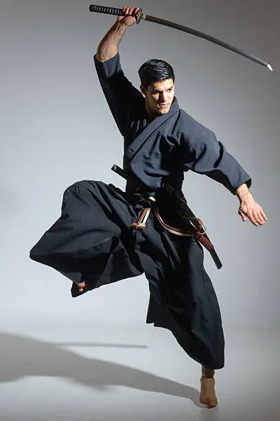 A Japanese swordsman is in expectant attitude straight to camera against white background