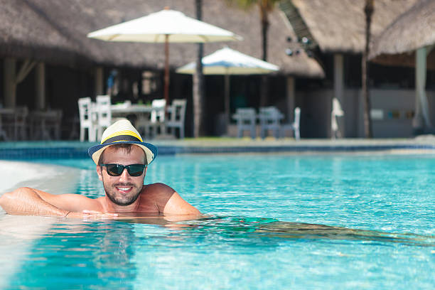 istock man wearing hat and sunglasses relaxing at the pool 494152131