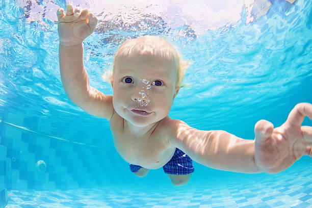 portrait of baby boy swimming and diving underwater in pool - baby swim under water bildbanksfoton och bilder