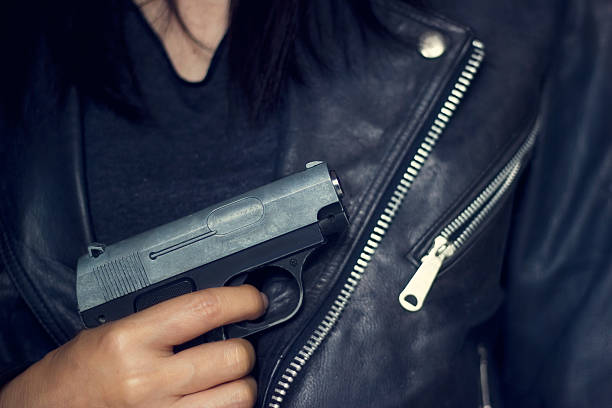 mujer con la pistola en la mano en la chaqueta negra - gun women handgun armed forces fotografías e imágenes de stock