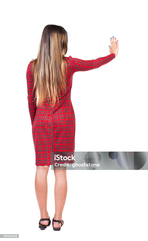 back view of young woman presses down on something back view of young woman presses down on something. Isolated over white background. Rear view people collection. backside view of person. Long-haired girl in a red plaid dress presses a button with your right hand. Buttocks Stock Photo