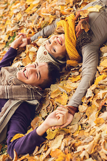 istock Happy couple lying down in leaves and laughing. 494161434