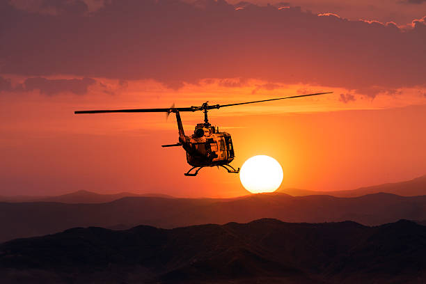 UH-1 Military Helicopter in flight at sunset UH-1 Military Helicopter on sunset background  uh 1 helicopter stock pictures, royalty-free photos & images