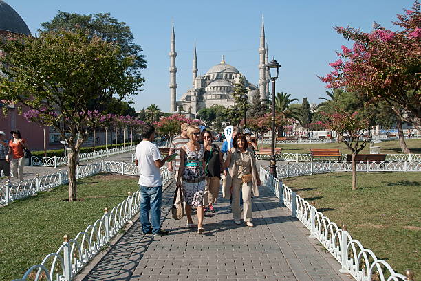Turkish guide leads tourist group from Blue Mosque, Istanbul, Turkey. stock photo