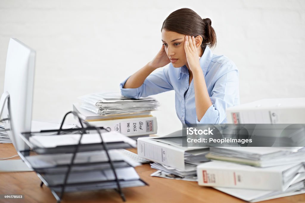 This is mind-numbing work A young businesswoman looking overwhelmed while surrounded by paperwork File Folder Stock Photo